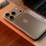 Overhead-view-of-an-iPhone-17-Pro-concept-lying-on-a-wooden-desk-next-to-a-laptop-and-AirPods-showing-its-potential-new-horizontal-camera-bar-design-and-Apple-logo.jpg