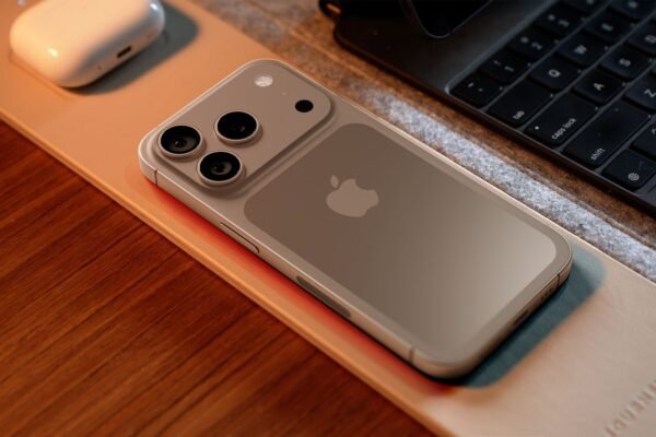 Overhead-view-of-an-iPhone-17-Pro-concept-lying-on-a-wooden-desk-next-to-a-laptop-and-AirPods-showing-its-potential-new-horizontal-camera-bar-design-and-Apple-logo.jpg
